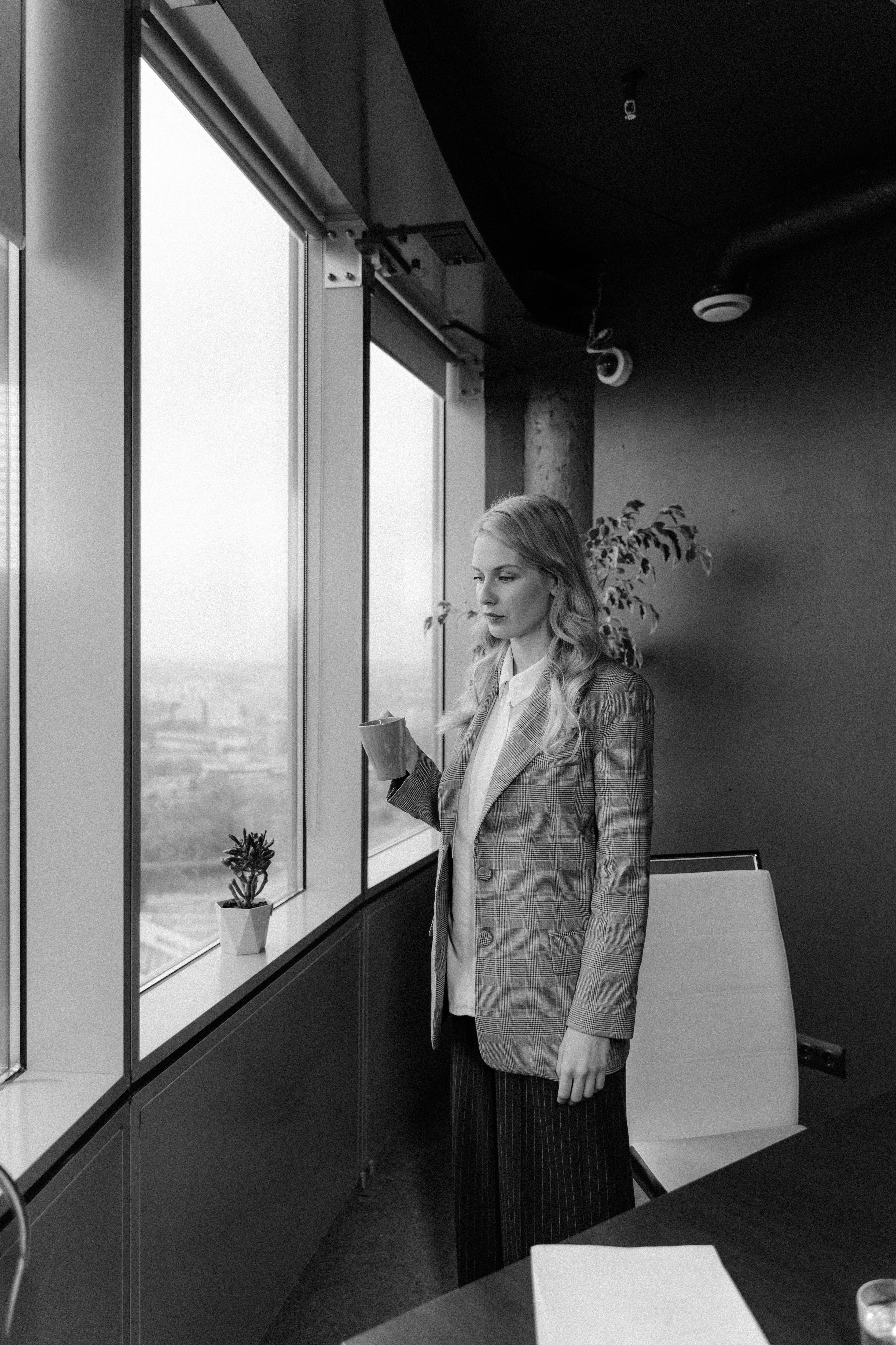 woman in a blazer standing beside window