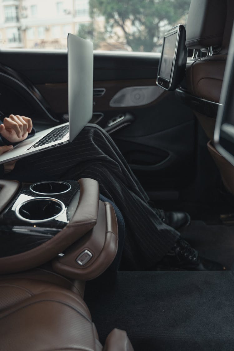 Person Seated At The Back Seat Using Macbook