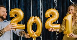 夫妇在室内手握金气球，微笑庆祝2021年新年