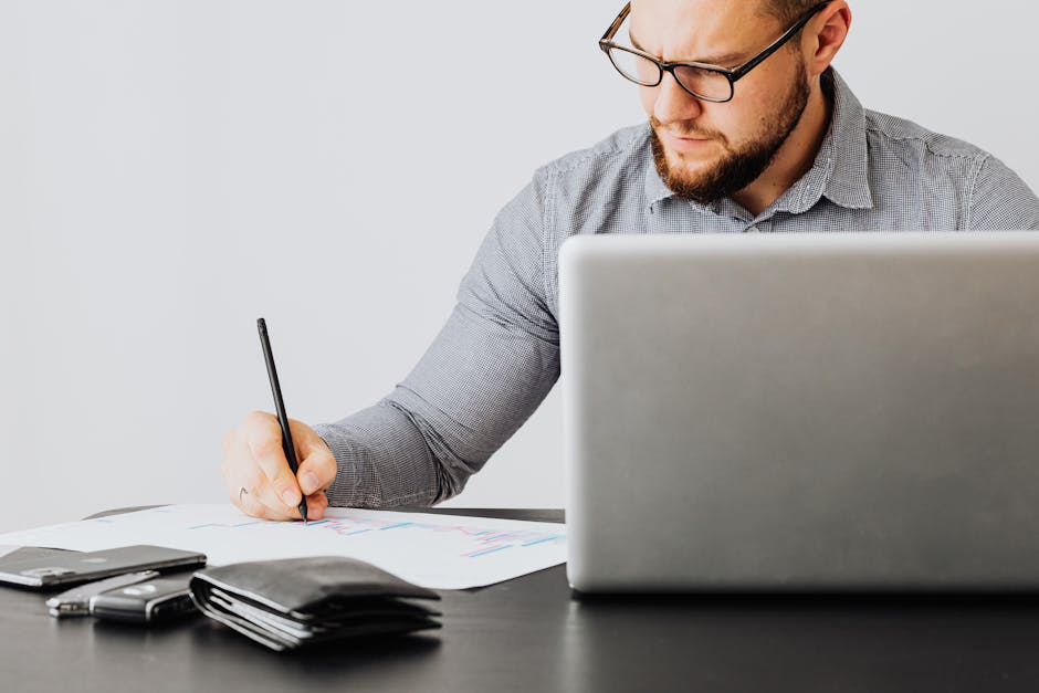 Stop Overpaying — Try Smarter Auto Coverage Savings A focused man analyzing financial papers with a laptop in an office setting.