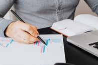 业务分析师在室内用笔记本电脑检查纸上的图形