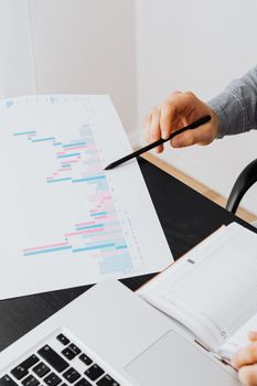 专业人士在办公室用笔记本电脑分析纸上的数据图表