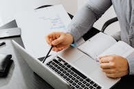 专业人员在办公桌前使用笔记本电脑查看文档，进行数据分析