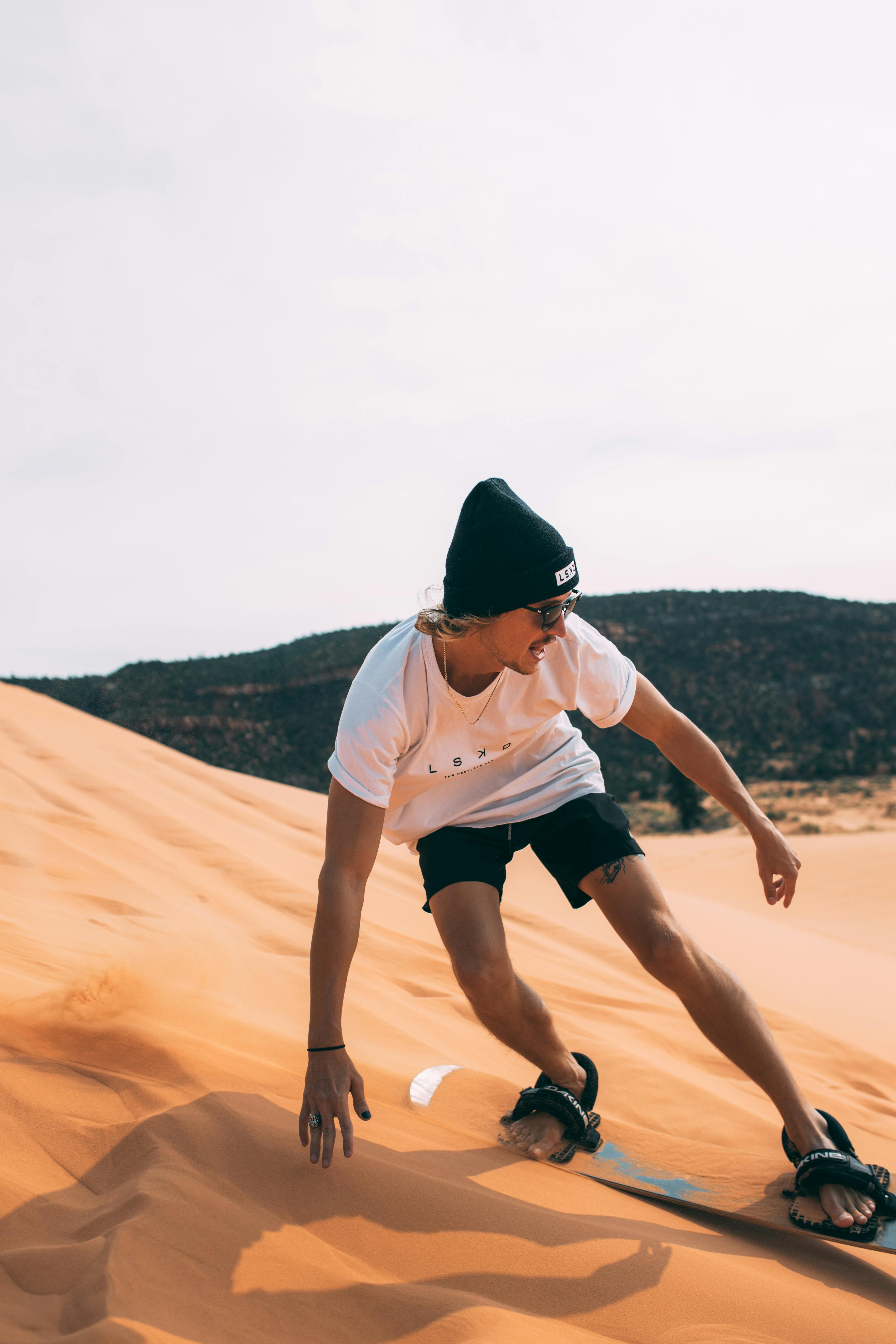 Gratis Mujer En Camiseta Blanca Y Pantalones Cortos Negros Corriendo Sobre Arena Marrón Foto de stock