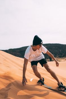 一名男子在犹他州阳光明媚的沙漠沙丘上滑沙，拥抱自然与冒险