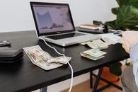 工作区里放着现金、笔记本电脑和显示投资分析的财务图表
