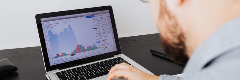 Man working on a laptop analyzing business data and financial graphs indoors.