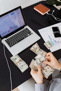 在桌子上用笔记本电脑分析财务趋势的人正在计算现金