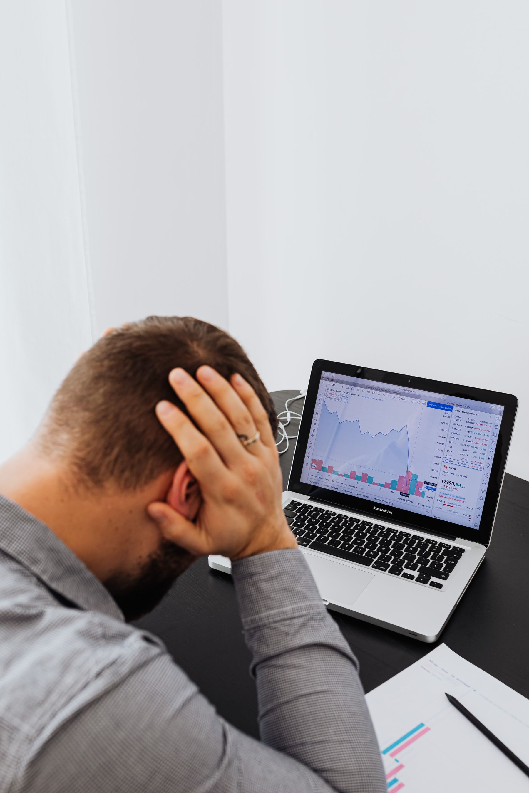 Geschäftsmann unter Druck vor Finanzcharts am Laptop