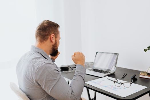 Businessman analyzing data on laptop with charts at modern workspace.