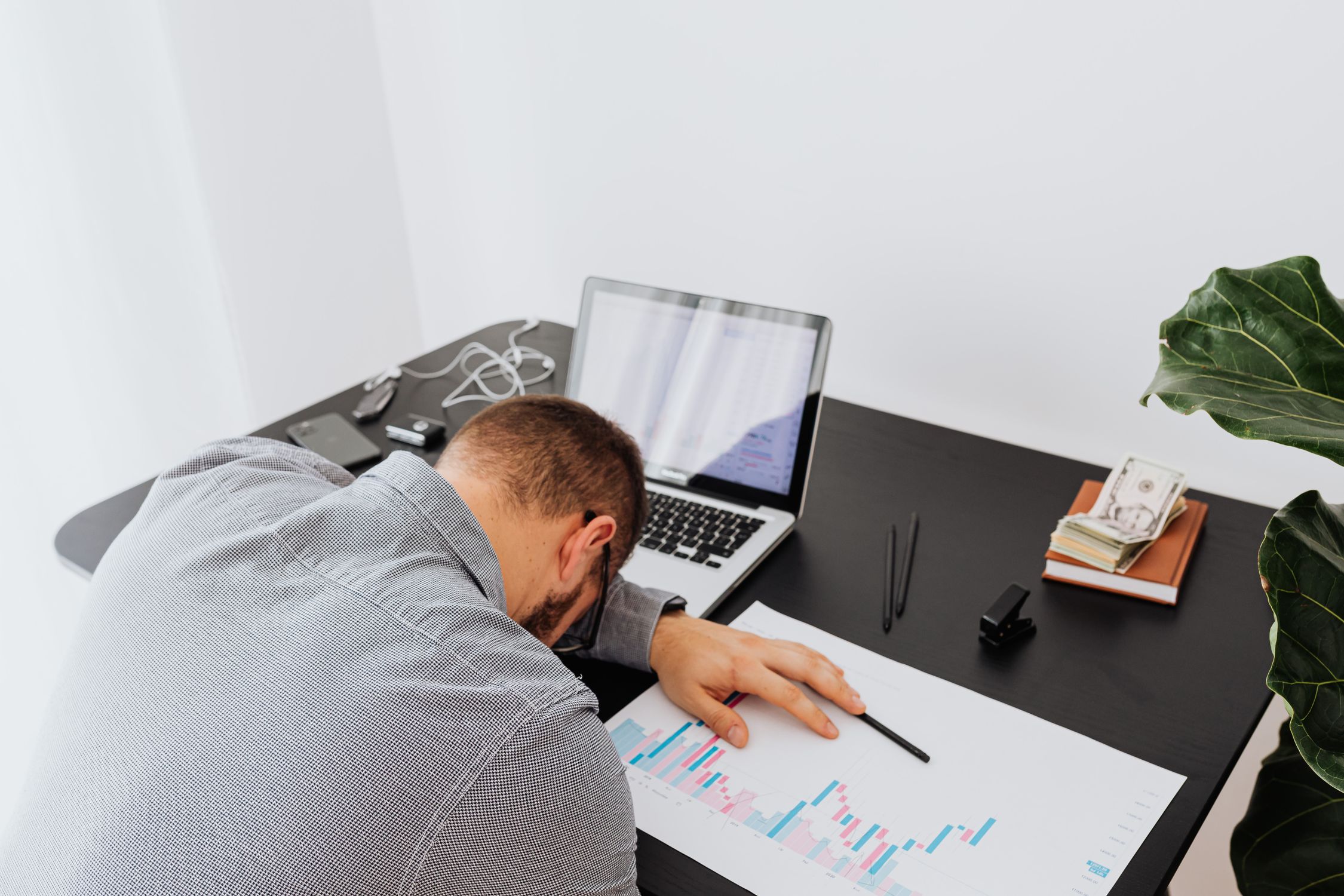 Trader slumped at desk with laptop and charts — the exhaustion after a forex account blow
