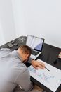 疲惫的人趴在桌上睡着了，周围堆满了工作物品，描绘出压力的氛围