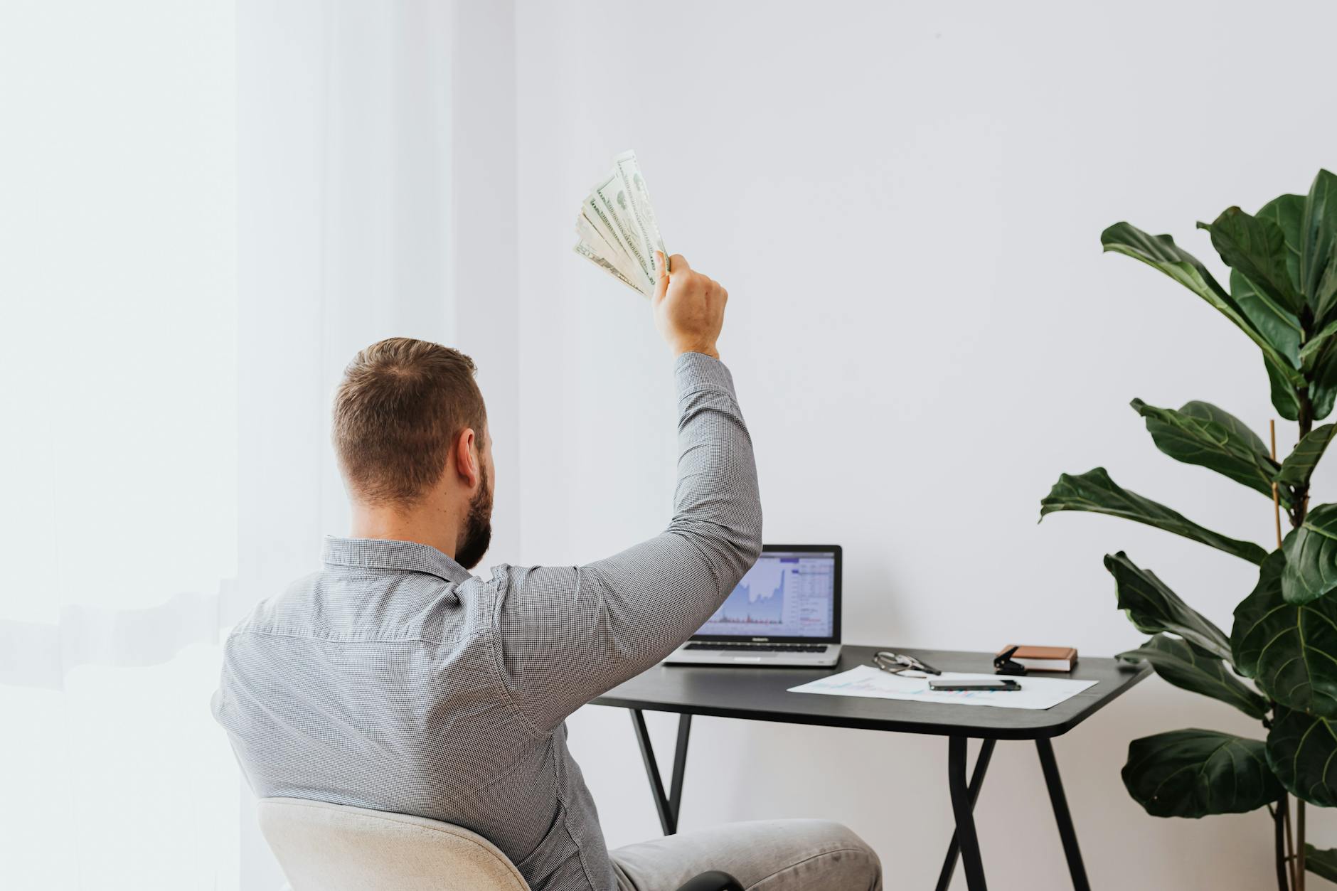 Quick Cash Loans in India: A Guide for Self-Employed Individuals 6 A man in a home office raises cash, symbolizing financial success and achievement.