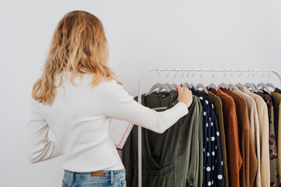 Back view of a woman browsing clothes on a rack in a boutique store.