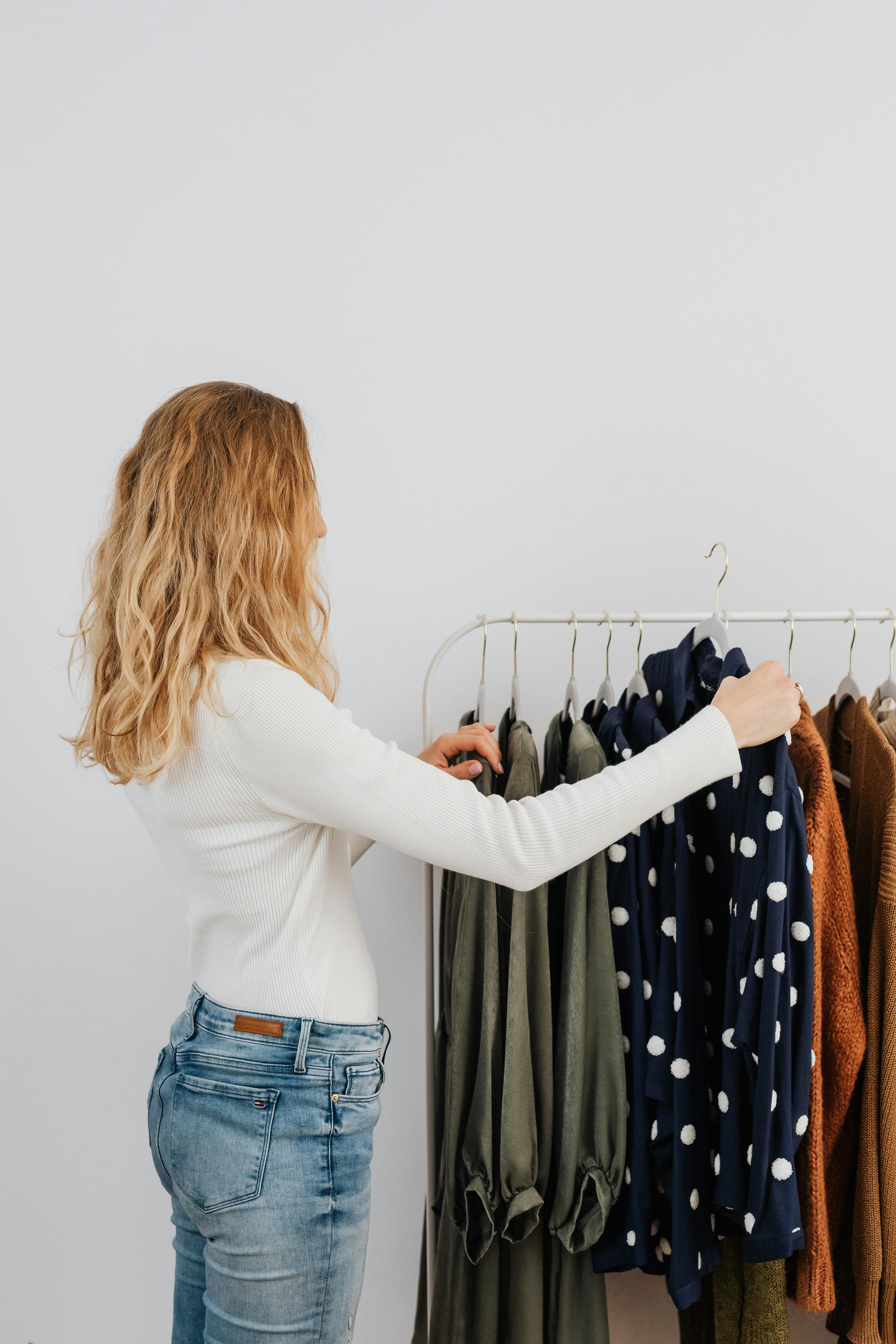 woman in white long sleeves looking at clothes