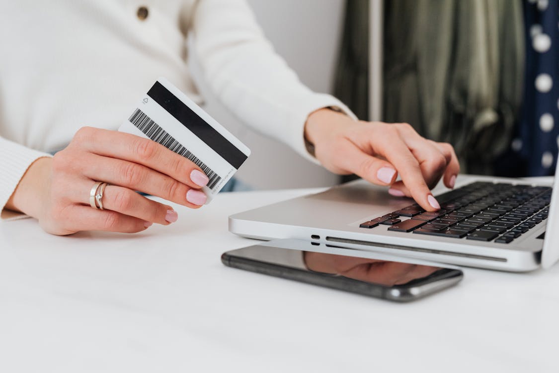 Free Person Using a Laptop and Holding a Credit card Stock Photo