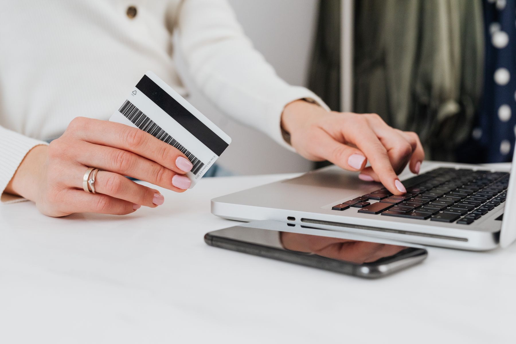 Person using a laptop while holding a credit card