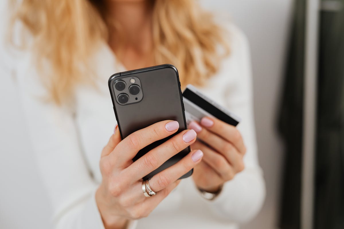 Primo piano di una mano che tiene smartphone e carta di pagamento