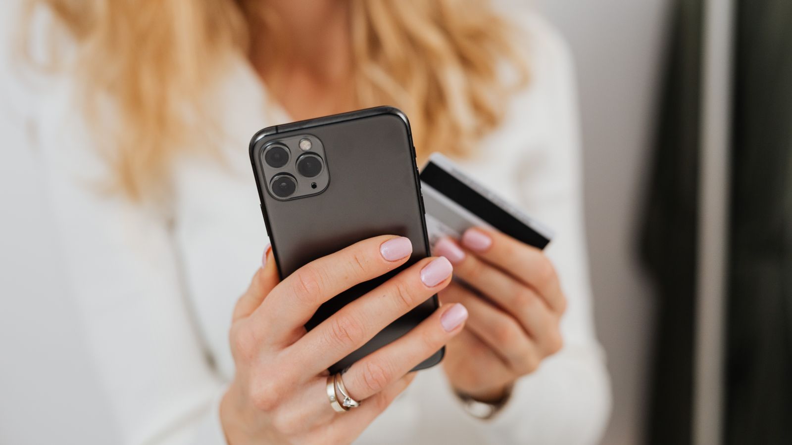 Persona sosteniendo una tarjeta de crédito y un smartphone