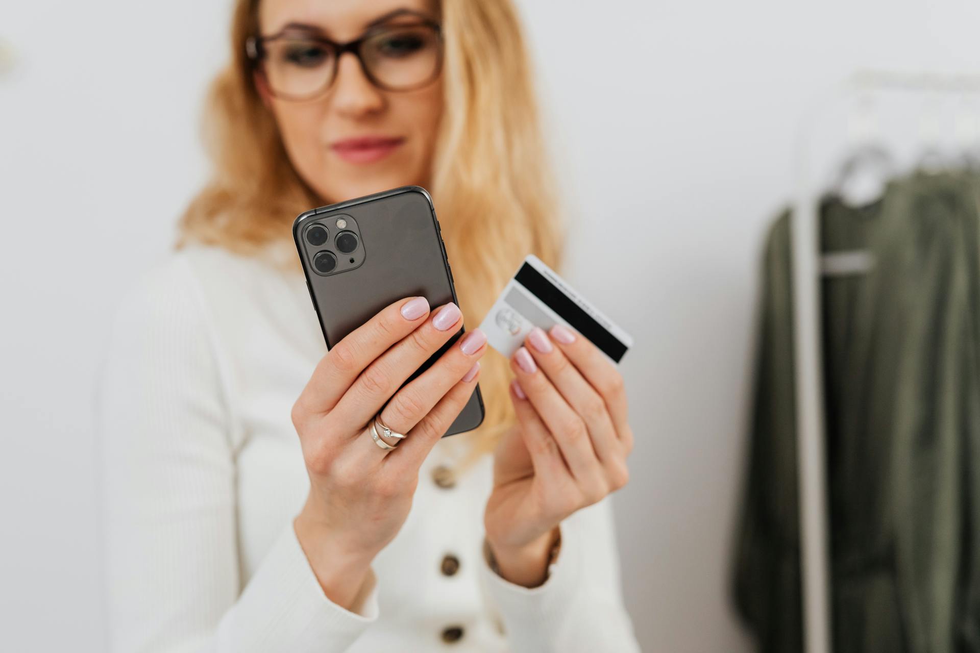 A woman holding a smartphone and credit card, engaging in online shopping indoors.