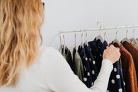 一位女士在精品店里专注地浏览着悬挂的衣服