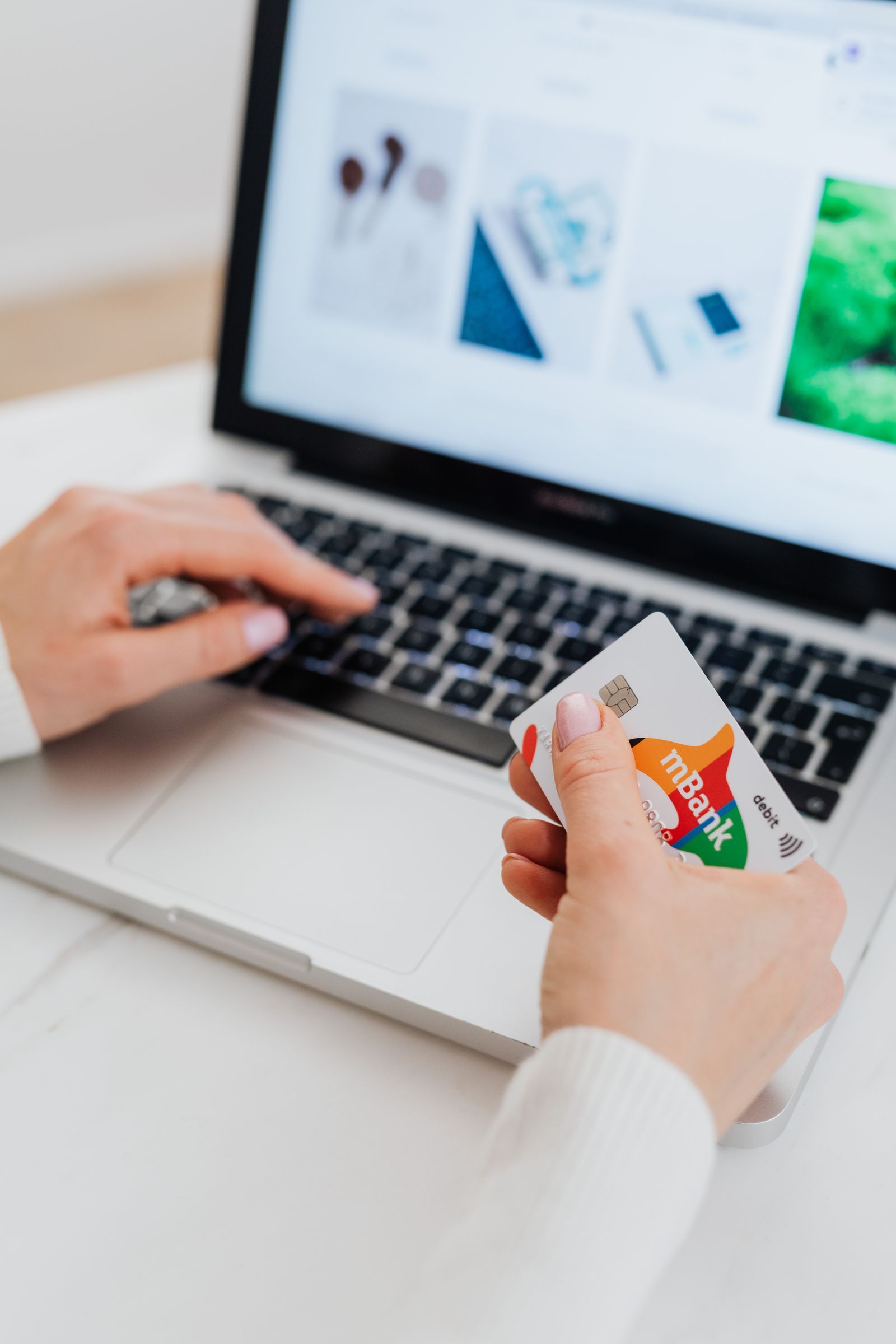 Hands using a payment card with a computer during an online purchase