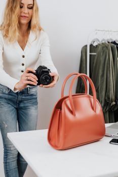 A woman in casual attire taking a photo of a stylish handbag indoors, highlighting modern fashion photography.