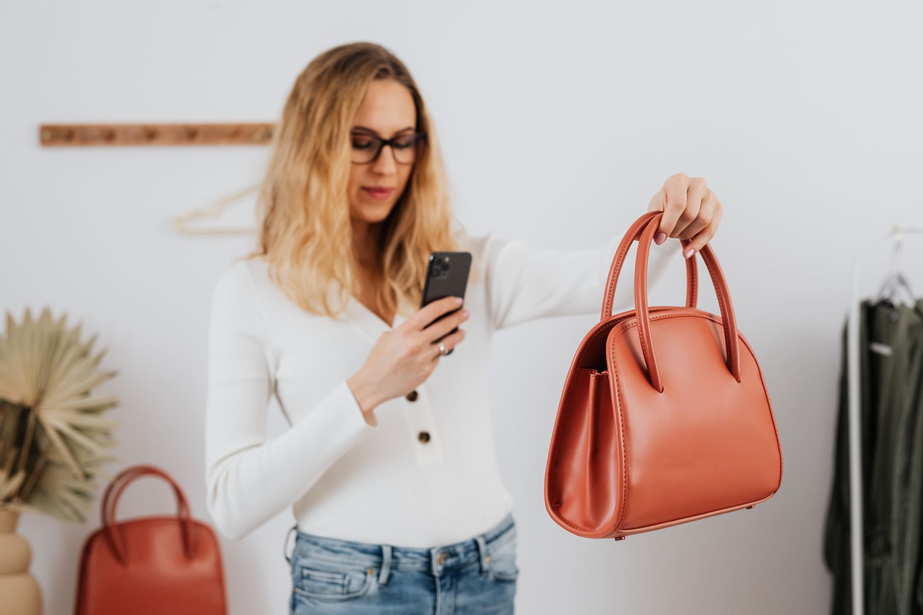 Une femme photographie un sac à main en cuir élégant avec son smartphone pour une vente en ligne.
