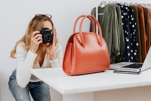 Free A Woman in White Long Sleeves Taking Photos of a Handbag Stock Photo
