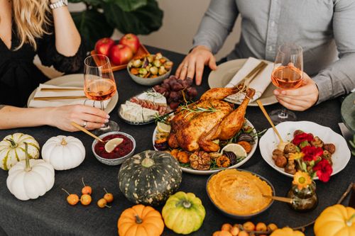 Free A warm and inviting Thanksgiving dinner setup featuring turkey, wine, and autumn vegetables. Stock Photo