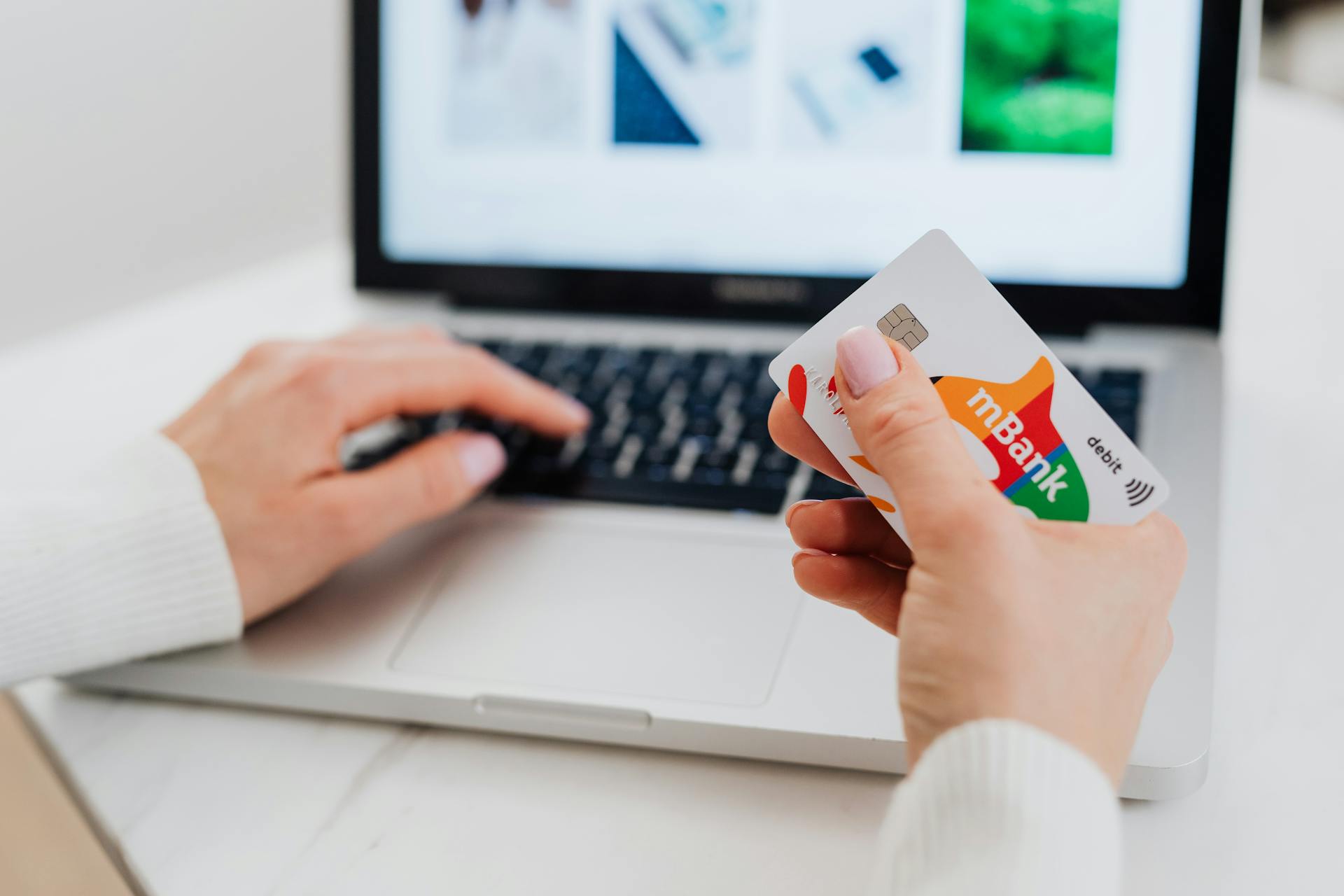 Close-up of hands using a laptop and holding a credit card for an online transaction.