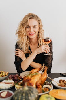 Blonde woman in black with wine glass enjoying a festive meal indoors.