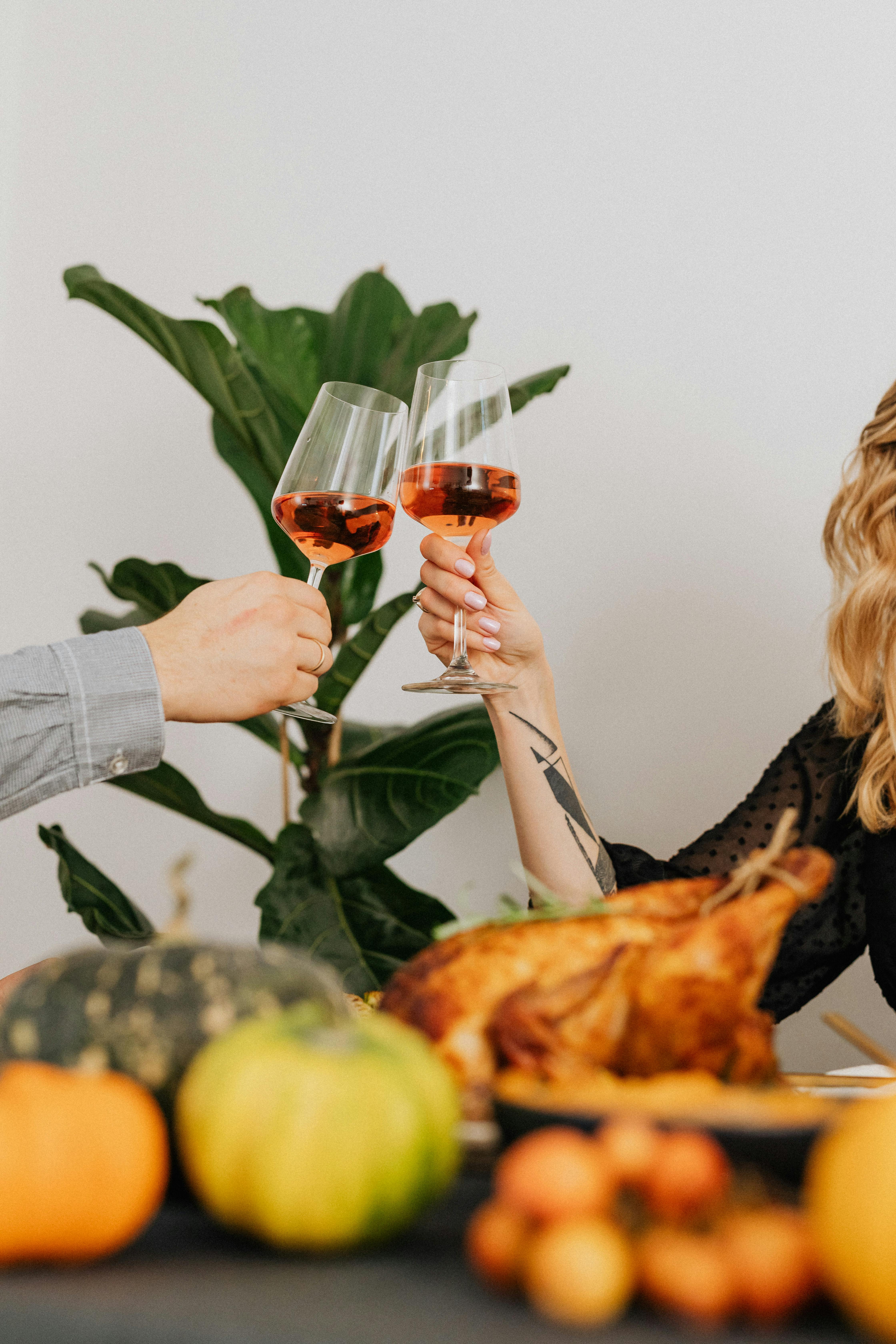 Adults toasting with glasses of rosé wine over a festive Thanksgiving table setting.