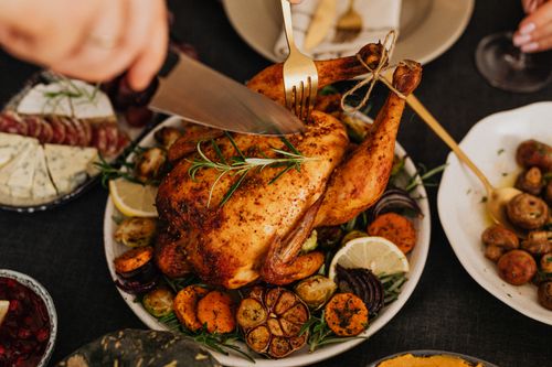 Free Close-up of a roasted chicken being carved, garnished with rosemary, lemon, and vegetables. Stock Photo