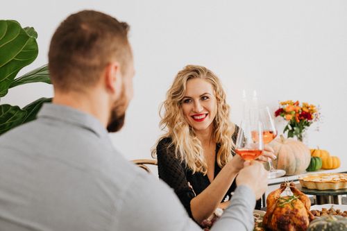 Free A couple enjoys a romantic dinner indoors, toasting with wine and sharing a joyful moment. Stock Photo