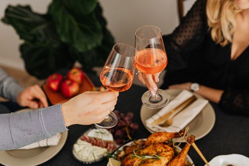 Free Couple toasting with wine over a delicious roasted chicken dinner. Stock Photo