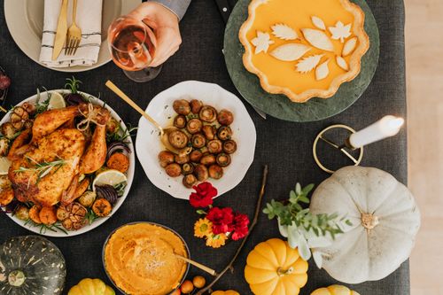 Free A top-down view of a festive autumn dinner featuring roast chicken, pumpkin pie, and various side dishes. Stock Photo