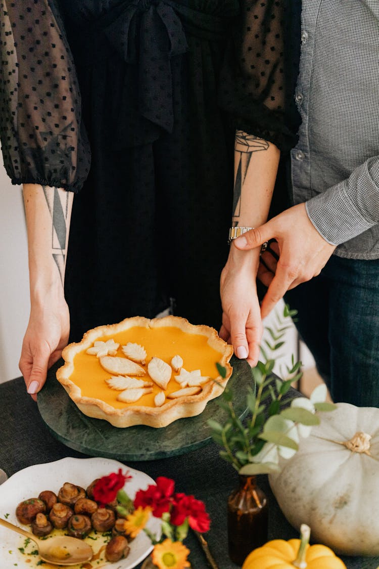 Couple Serving Pumpkin Pie At Table