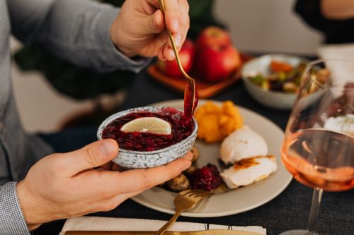 Free A man enjoys an elegant dinner with cranberry sauce, showcasing fine dining. Stock Photo
