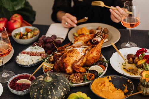 Free A festive Thanksgiving dinner spread featuring a golden roasted turkey, vegetables, and wine, perfect for holiday dining. Stock Photo