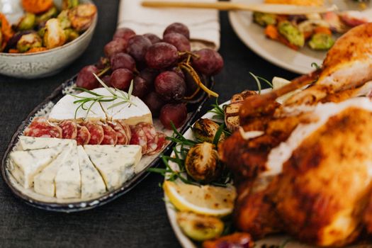 A mouth-watering charcuterie board featuring blue cheese, salami, grapes, and roasted chicken.