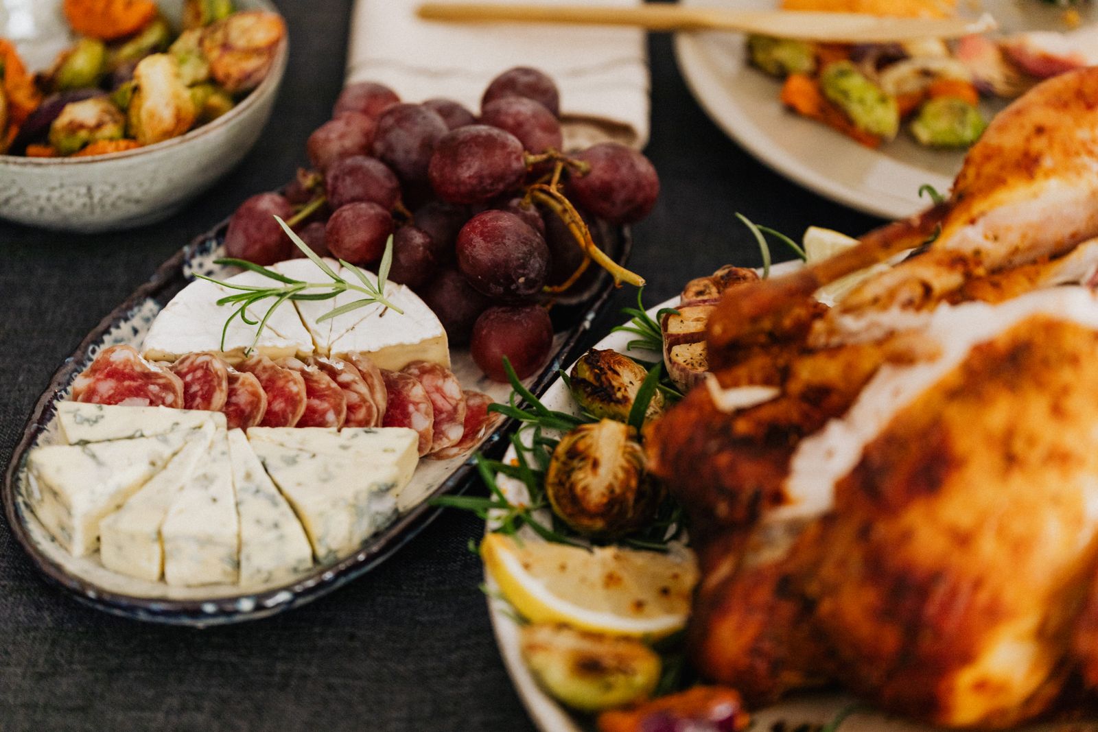 A mouth-watering charcuterie board featuring blue cheese, salami, grapes, and roasted chicken.