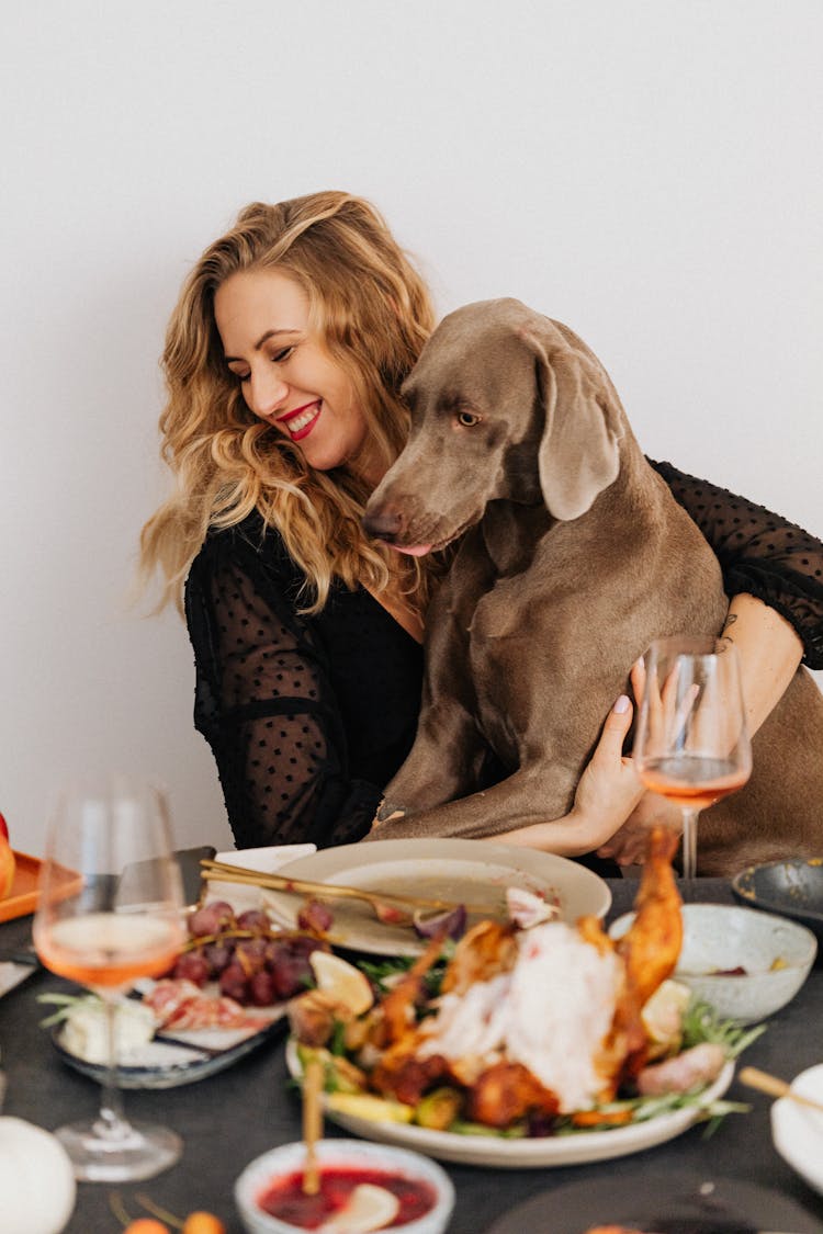 Woman With Dog And Dinner On Table