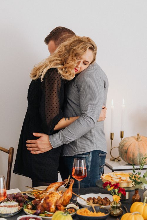 Free A loving couple embraces at a beautifully set fall dinner table with roasted chicken and autumn decor. Stock Photo