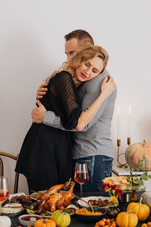 Free Couple hugging over a festive fall dinner with roasted chicken and pumpkins. Stock Photo