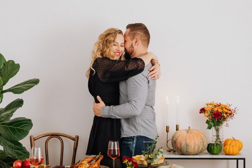 Free Caucasian couple embracing during a cozy Thanksgiving dinner with autumn decorations. Stock Photo