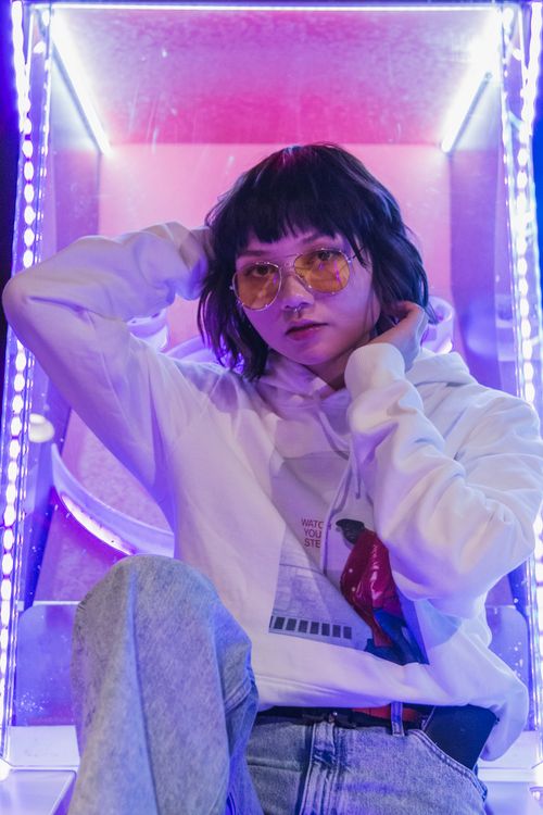 Free Stylish portrait of a woman with sunglasses under neon lights, posing with attitude. Stock Photo