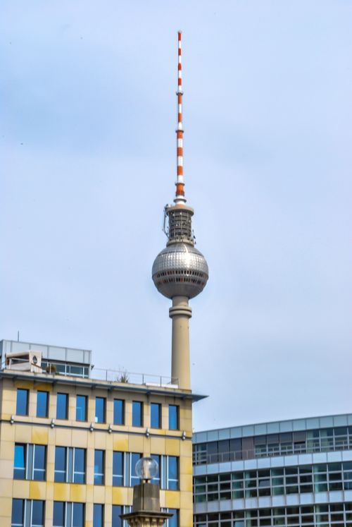 Free View of the Berlin TV Tower rising above the city's architectural skyline on a clear day. Stock Photo