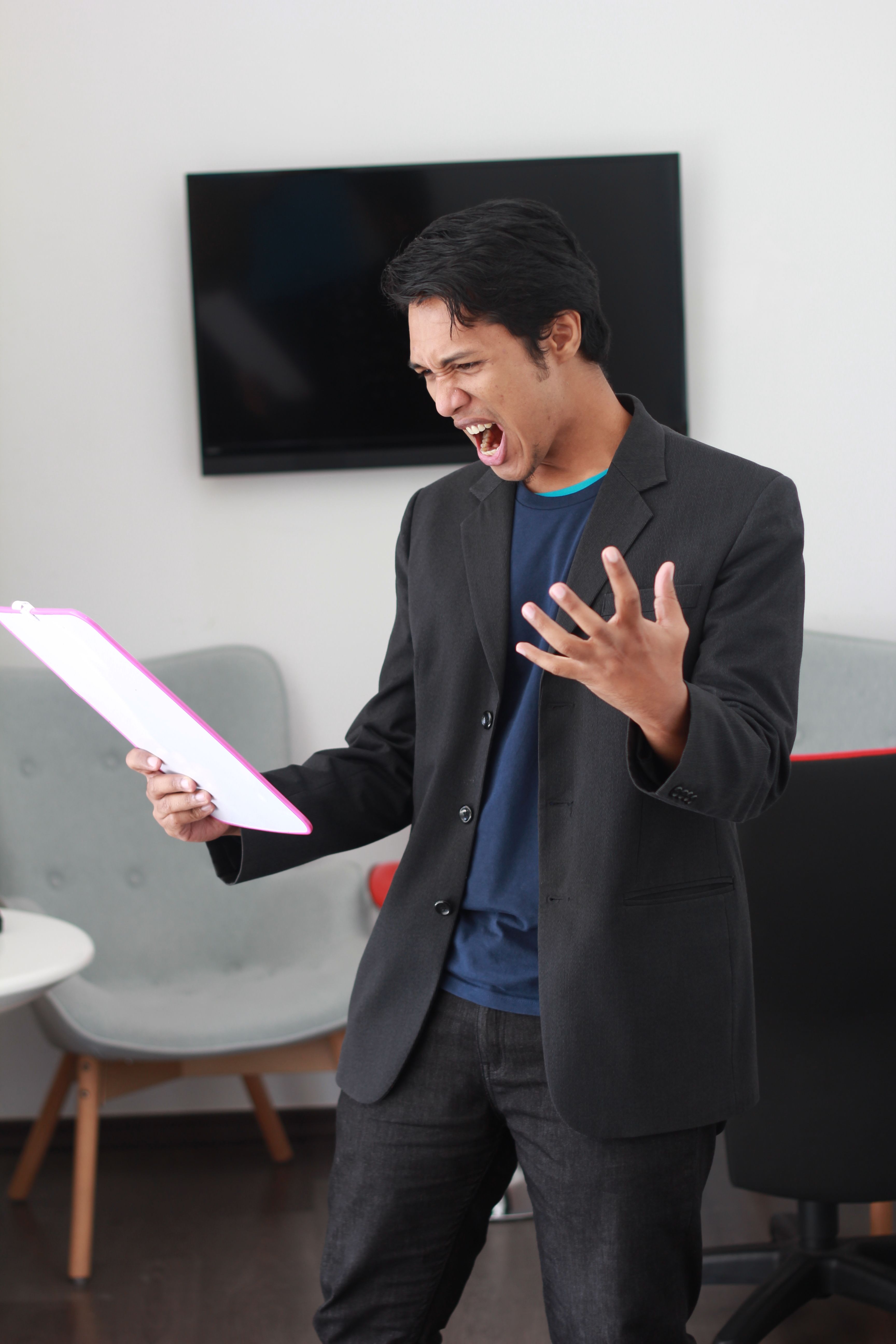 穿着黑色西装的商务人士在办公室拿着文件时会情绪激动