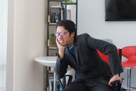 Businessman in a black suit experiencing stress while sitting in a modern office in Malaysia.